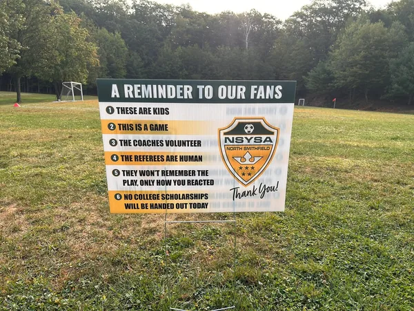 An NSYSA sign at the field reminding spectators that these are kids, this is a game, the coaches volunteer and the referees are human