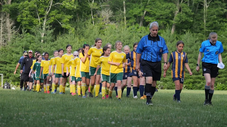 Two NSYSA teams walk onto the field behind the referee before a Saturday match