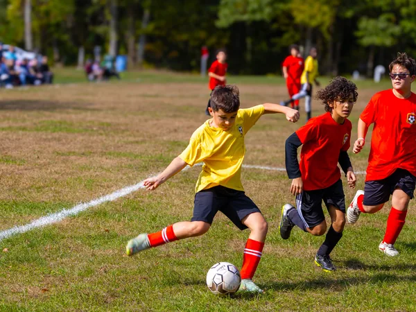 An NSYSA player drives the ball upfield as two defenders close in during a Saturday match